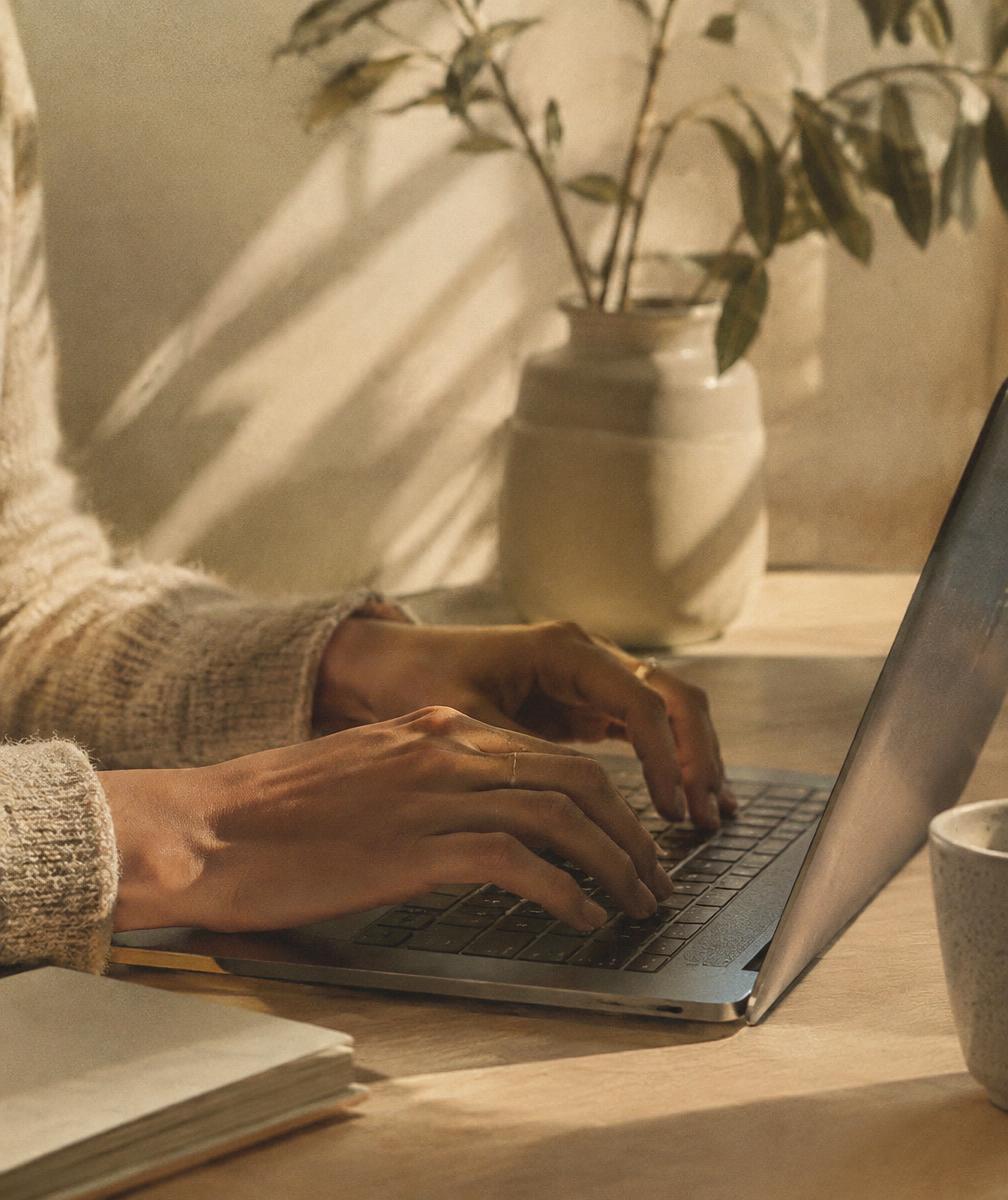 Hands working on a laptop in a sunlit studio
